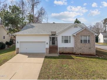 Charming home with a two-car garage, manicured lawn, brick accents, and mature trees offering curb appeal at 100 W Acres Cres, Cary, NC 27519