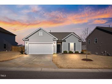 Charming single-story home with gray siding, a two-car garage, and a well-manicured front lawn at dusk at 1008 Sandtrap Way, Durham, NC 27703