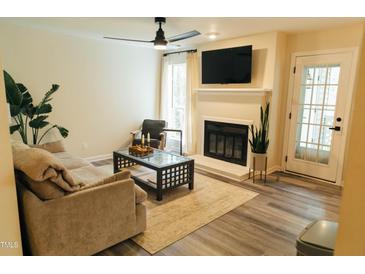 Inviting living room featuring a fireplace, ceiling fan, and neutral color palette, with an adjacent exterior door at 106 Choptank Ct # B3, Cary, NC 27513