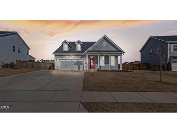 Charming single-Gathering home with a two car garage, manicured lawn, and a welcoming red front door at 1112 Leatherstone Ln, Fuquay Varina, NC 27526