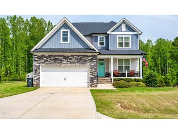 Charming two-story home showcasing a stone facade, attached garage, and inviting front porch with a vibrant turquoise door at 201 Northview Dr, Middlesex, NC 27557