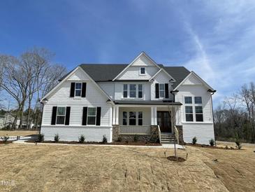 Stunning two-story home featuring white brick and siding, black shutters, and a welcoming front porch at 289 Streamside Dr, Angier, NC 27501