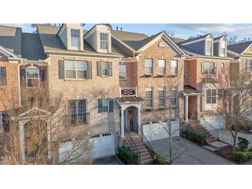 Charming brick townhome featuring detailed architectural elements and manicured landscaping in an inviting neighborhood at 3003 Weston Green Loop, Cary, NC 27513