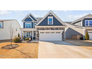 Charming two-story home with a two car garage, blue siding, stone accents and well-manicured lawn at 706 Tibumoll Ln, Fuquay Varina, NC 27526
