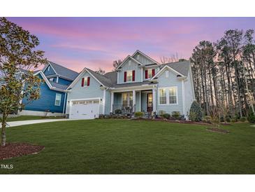 Charming two-story home features a manicured lawn, two-car garage, and inviting front porch at 1129 Sequoia Creek Ln, Cary, NC 27519