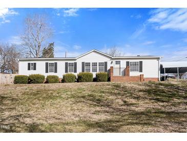 Charming single-story home with white siding, dark shutters, and a well-maintained front yard at 136 Pelham St, Haw River, NC 27258