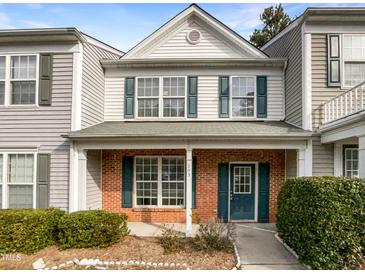Charming two-story home with a brick facade and teal shutters, showcasing classic curb appeal in a townhome at 203 Canyon Lake Cir, Morrisville, NC 27560