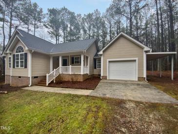 Inviting single story home with attached garage and covered portico, surrounded by mature trees and landscaped grounds at 4050 Brooksdale Dr, Franklinton, NC 27525