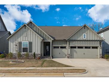 Charming home featuring a three car garage, stone accents, a well kept lawn, and board and batten siding at 50 Sneed Ln, Fuquay Varina, NC 27526