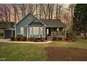 Charming single-Gathering home boasts a cozy front porch and inviting curb appeal with mature landscaping at 115 N Oakland Dr, Mebane, NC 27302