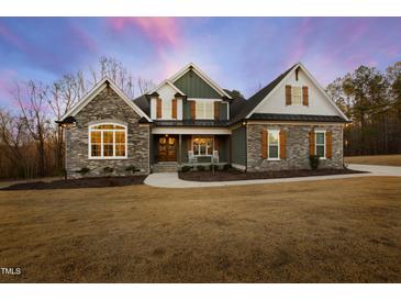 Charming two-story home boasting a stone facade, inviting front porch, and manicured lawn in a serene setting at 1636 Sweetwater Ln, Raleigh, NC 27610