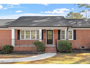 Charming brick home featuring a covered front porch, black shutters and lush landscaping at 200 Arlington Cir Cir, Sanford, NC 27330