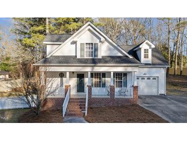 Charming two-story home with a brick foundation, covered porch, and a well-manicured front yard at 214 Linville Ln, Willow Springs, NC 27592