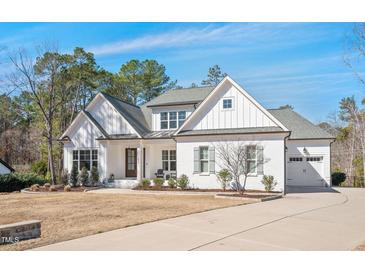 Inviting white brick home featuring a manicured lawn and mature trees at 2412 Toll Mill Ct, Raleigh, NC 27606