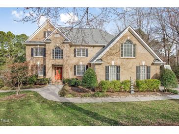 Elegant brick home with a manicured front lawn and mature landscaping, showcasing its classic design at 102 Shepton Dr, Cary, NC 27519