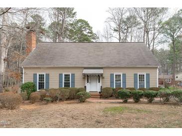 Charming single-story home with a brick chimney and landscaped front yard with inviting blue shutters at 115 Perth Pl, Durham, NC 27712