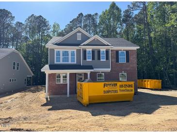 Two-story home with gray siding, brick accents, black shutters, and visible dumpster at 1849 Ballard Rd # Holly Georgian, Fuquay Varina, NC 27526