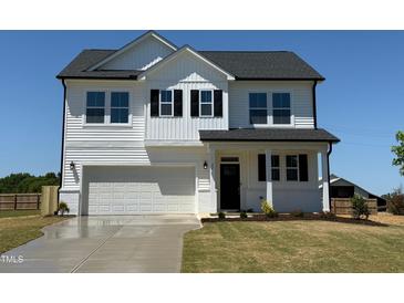 Charming two-story home with a manicured lawn, black shutters, and a convenient attached two-car garage at 22 Whistling Way # Holly Farmhouse, Lillington, NC 27546