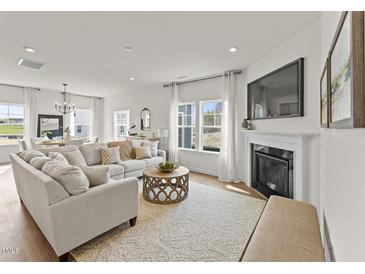 Bright living room with a fireplace, large sofa, and an ornate coffee table at 509 Marthas View Way, Wake Forest, NC 27587