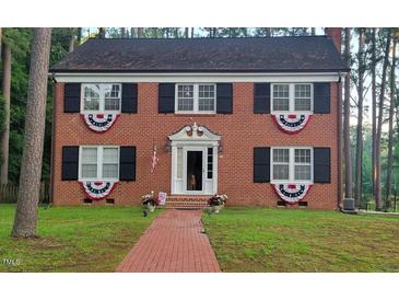 Charming brick two-story home featuring black shutters, brick walkway and decorative patriotic bunting at 636 Palmer Dr, Sanford, NC 27330