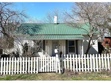 Charming home featuring a picket fence and a vibrant green metal roof at 108 Holt St, Hillsborough, NC 27278