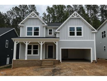 Charming two-story home with a covered porch, an attached two-car garage, and stylish gray siding at 122 Sanderway Dr, Chapel Hill, NC 27516