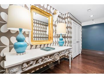 Hallway featuring a unique wallpaper pattern, hardwood floors, and ornate console table with elegant lamps at 140 W Franklin St # 406, Chapel Hill, NC 27516