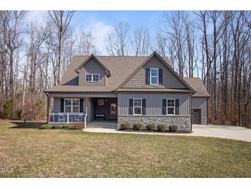 Charming home featuring a stone accent base, gray siding, dormers, and a welcoming front porch at 193 Jenny Ln, Timberlake, NC 27583