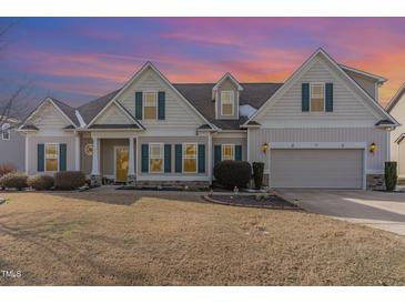 Charming two-story home featuring beige siding, green shutters, and a manicured lawn in a suburban neighborhood at 32 Colson Dr, Garner, NC 27529