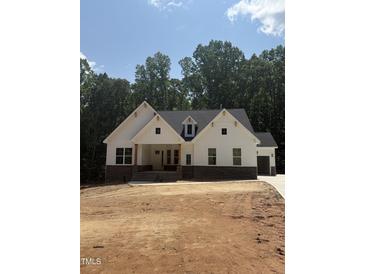 New construction home with white siding, stone accents, and a well-lit front porch at 60 Valebrook Ct, Youngsville, NC 27596