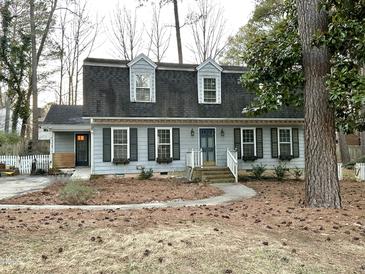 Charming two-story home with gray siding, dark shutters, dormer windows, and a blue front door at 6709 Sunhaven Pl, Raleigh, NC 27615