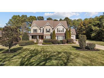 Traditional home with mature landscaping, a well-manicured lawn, and a welcoming front porch at 690 Hawthorne Pl, Creedmoor, NC 27522