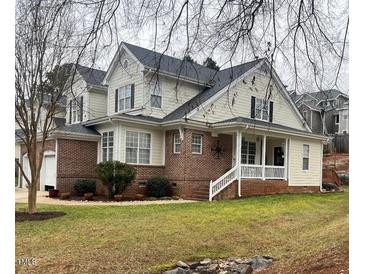 Charming brick and siding home featuring a covered porch and well-maintained landscaping at 7710 Astoria Pl, Raleigh, NC 27612