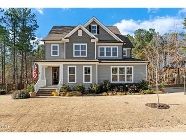 Charming two-story home with gray siding, white trim, landscaped yard, and an American flag displayed on the porch at 2504 Georgianna Dr, Wake Forest, NC 27587