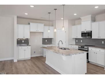 Bright kitchen features an island with marble countertops and pendant lighting at 277 Gregory Village Dr, Lillington, NC 27546
