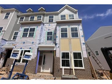 Under construction exterior elevation of a new brick townhome with a covered front porch, several large windows and a gabled roofline at 324 Chesapeak Commons St # 143, Garner, NC 27529