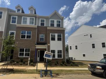 A charming brick townhome showcasing a modern facade with gray accents and well-maintained landscaping at 324 Chesapeak Commons St # 143, Garner, NC 27529
