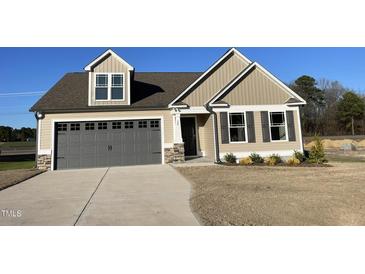 Charming tan home with a gray garage door, dormer window, and a well-manicured lawn at 39 Flatland Dr, Princeton, NC 27569