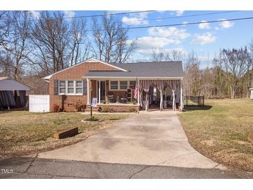 Charming brick home featuring a covered front porch, gray roof, and a well-maintained front yard at 74 Azalea Dr, Roxboro, NC 27573