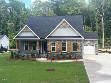 Charming single-Gathering home featuring a stone facade, a manicured lawn, and an attached two-car garage at 80 Valebrook Ct, Youngsville, NC 27596