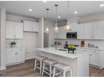 Bright kitchen features a large island with seating, stainless steel appliances, and modern lighting at 82 Fairwinds Dr, Lillington, NC 27546
