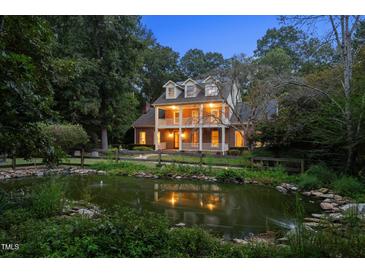 Beautiful two-story brick home with double balconies overlooking a serene pond at twilight at 1017 Holly Creek Ln, Chapel Hill, NC 27516