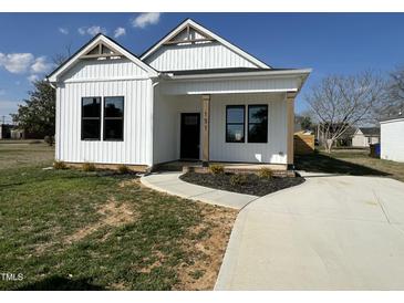 Charming new construction featuring a covered porch, black windows, and a manicured lawn at 151 E Washington St, Coats, NC 27521