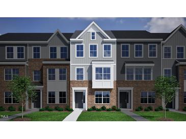 Beautiful brick townhome with gray siding, black door, and manicured front lawn at 336 Chesapeak Commons St # 140, Garner, NC 27529