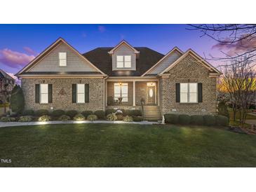 Charming brick home with manicured lawn, covered porch, and inviting curb appeal at dusk at 4278 Aviemore, Burlington, NC 27215