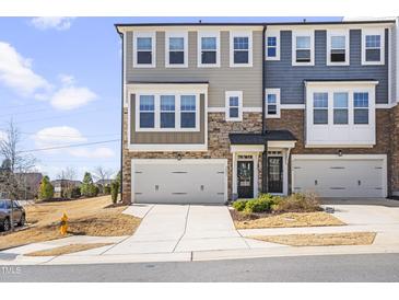 Beautiful townhome exterior featuring a stone and siding facade, two-car garage, and well-maintained landscaping at 8401 Zinc Autumn Path Path, Raleigh, NC 27615