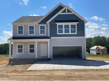 Charming two-story home with blue and gray siding, classic architectural details, and an attached two-car garage at 108 Grove Township Way, Angier, NC 27501