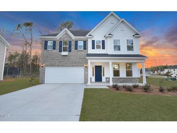 Charming two-story home features a brick and white facade, complemented by blue shutters and a well-manicured lawn at 2156 Pink Peony Cir # 157, Durham, NC 27703