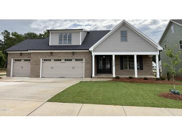 Charming home with a two car garage, gray and brick exterior, and a manicured front lawn at 2328 Eagle Shot Ct # 18, Fuquay Varina, NC 27526