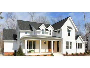 Charming white farmhouse with black roof, covered porch, and manicured landscaping at 431 Fieldstone Ln, Pittsboro, NC 27312